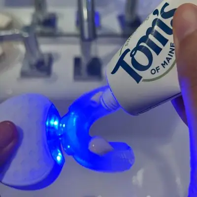 woman applying toothpast on SonicGlow